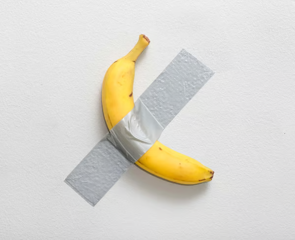 A banana taped to a white wall with gray duct tape